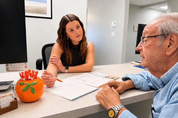 A patient and a team member talking across the consultation desk at Orange Blossom Oral Surgery