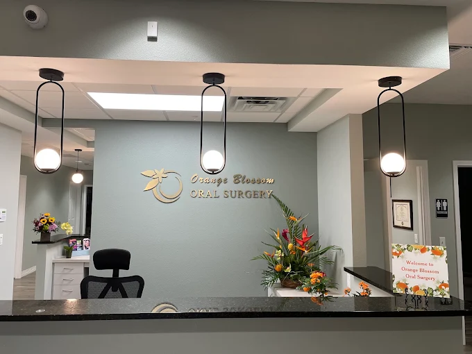 The Orange Blossom Oral Surgery reception desk, with the practice name in gold lettering on a sage green wall