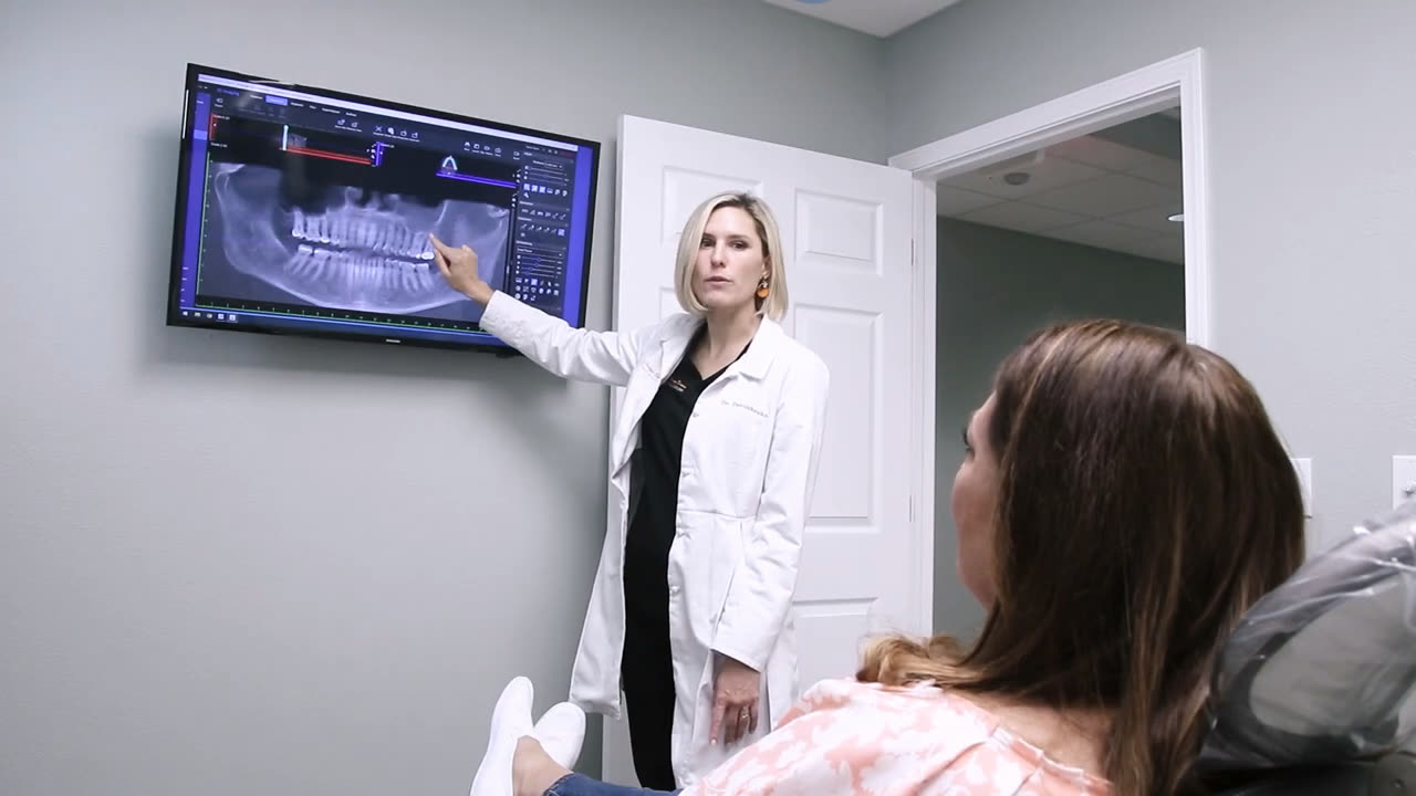 An Orange Blossom surgeon showing a patient the scan of her jaw before implant treatment